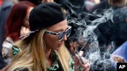 A woman smokes marijuana during the annual 4/20 marijuana gathering at Civic Center Park in downtown Denver.