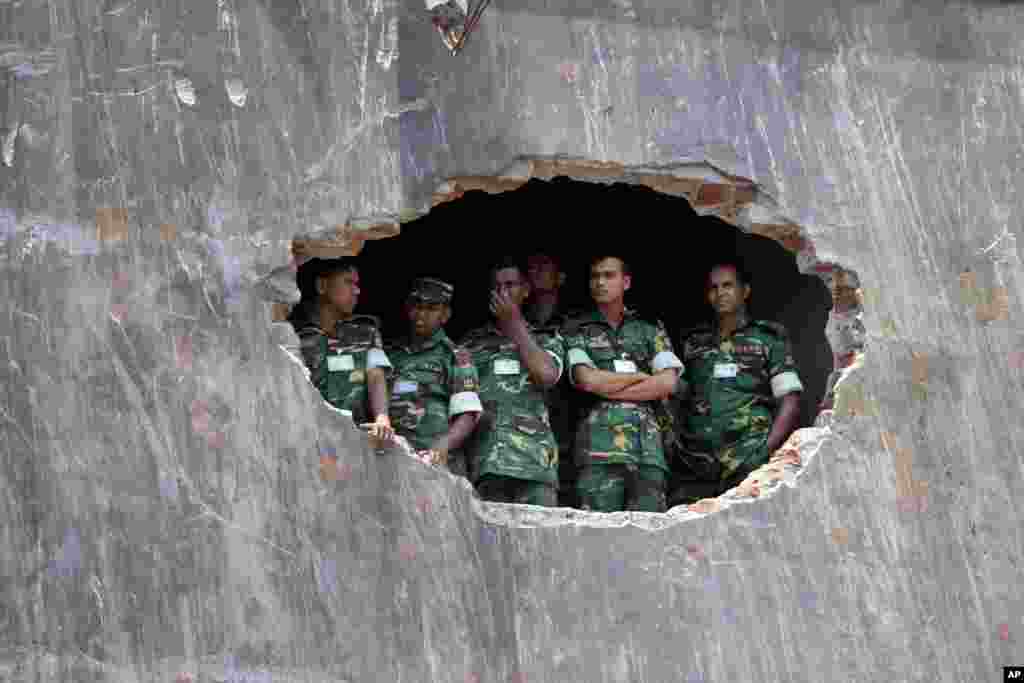 Bangladesh army soldiers watch a prayer ceremony for the souls of the 1,127 people who died in a garment building collapse last month, in Savar, near Dhaka. 