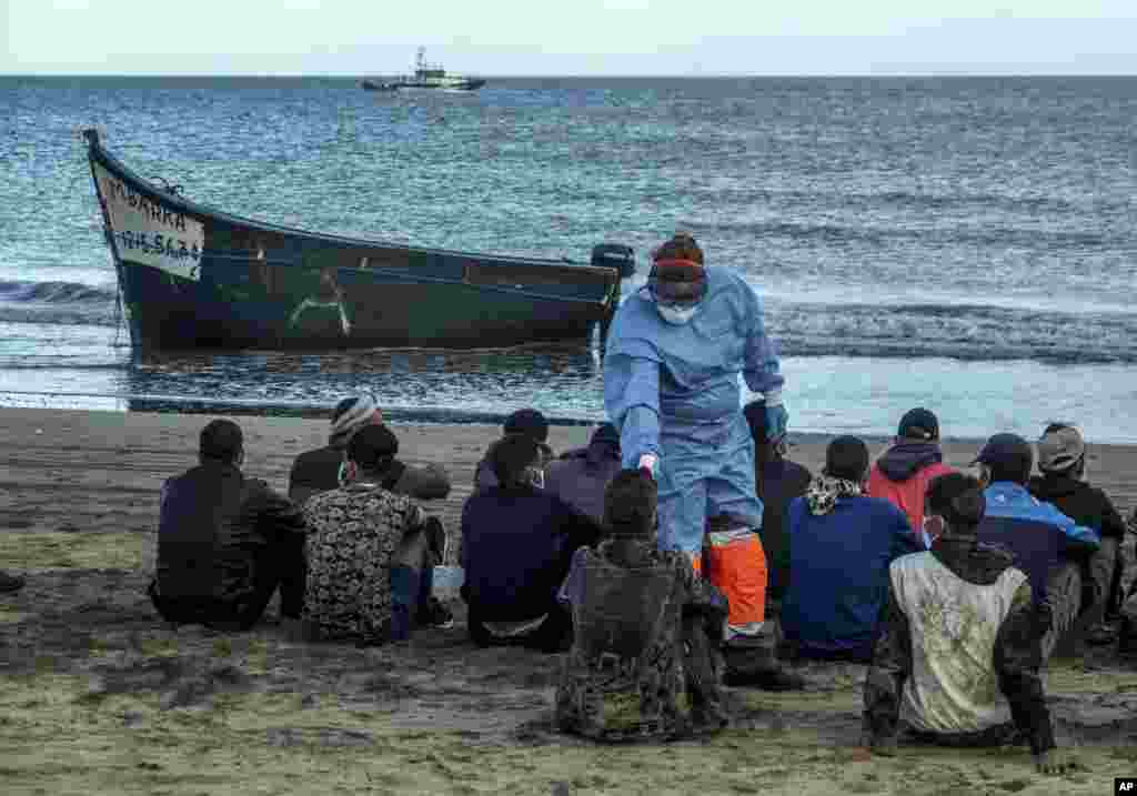 Migrants from Morocco have their temperature checked because of the coronavirus, upon arrival at the coast of the Canary Island, Spain, after crossing the Atlantic Ocean sailing on a wooden boat, Oct.20, 2020.