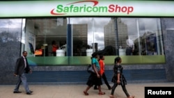 Pedestrians walk past a mobile phone care centre operated by Kenyan's telecom operator Safaricom in the central business district of Kenya's capital Nairobi, May 11, 2016.