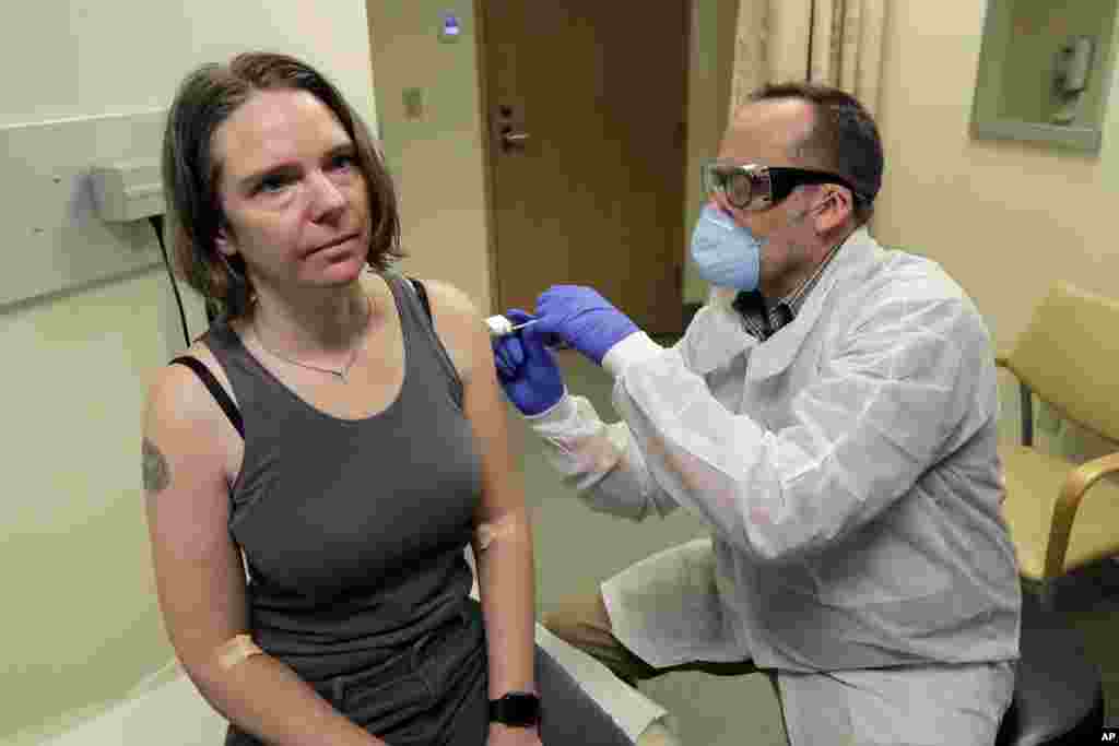A pharmacist gives Jennifer Haller, left, the first shot in the first-stage safety study trial of a possible vaccine for COVID-19, the disease caused by the new coronavirus, at the Kaiser Permanente Washington Health Research Institute in Seattle.