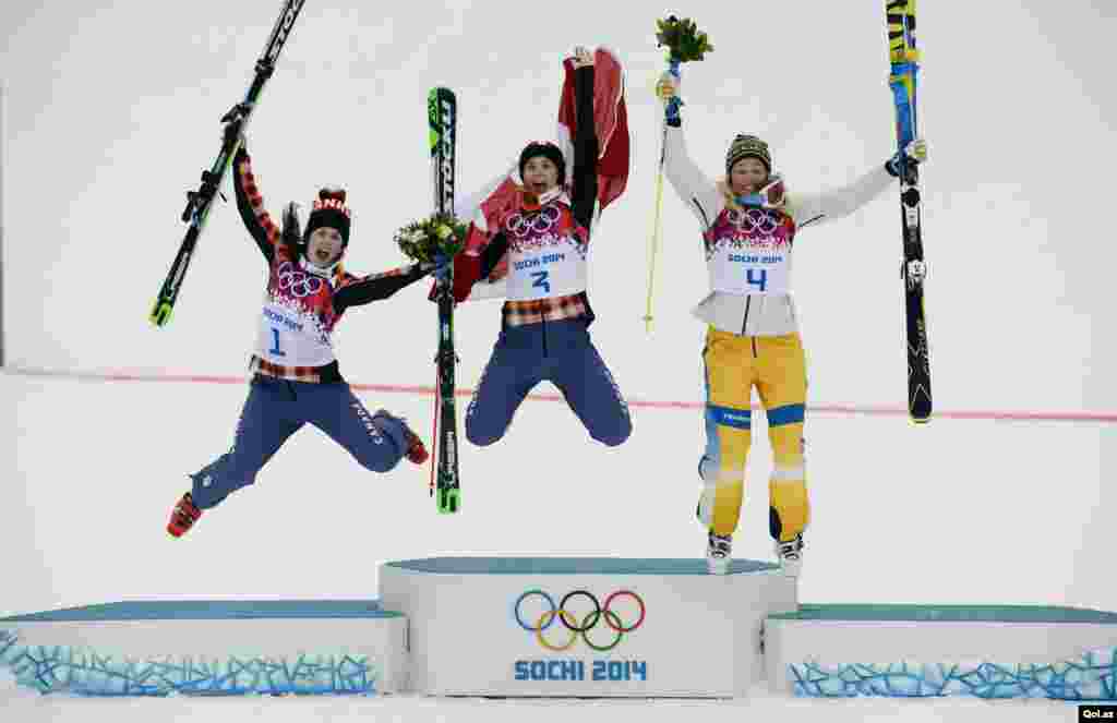 Canada's winner Marielle Thompson, second-placed compatriot Kelsey Serwa, and Sweden's third-placed Anna Holmlund (L-R) jump on the podium after the women's freestyle skicross finals at the 2014 Sochi Winter Olympic Games in in Rosa Khutor, Russia.