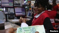 FILE: A till operator poses with new bond notes at a supermarket in Harare, Nov. 28, 2016.