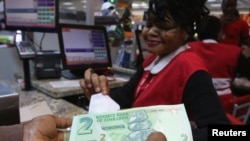 FILE: A till operator poses with new bond notes at a supermarket in Harare, Nov. 28, 2016.