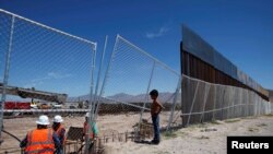 Seorang anak mengamati para pekerja AS yang tengah bekerja membangun tembok perbatasan AS-Meksiko di Sunland Park, New Mexico, yang berbatasan dengan kota Ciudad Juarez, Meksiko, 9 September 2016 (Foto: dok). 