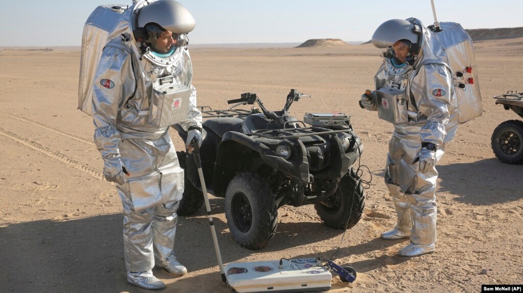 Two scientists test space suits and a device called a geo-radar for use in a future Mars mission in the Dhofar desert of southern Oman.