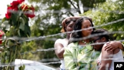 Area residents, from left, Waynetta Theodore, Alberta Harris and Christiena Preston console each other as they pay their respects at a makeshift memorial near the site where two Mississippi police officers were killed in Hattiesburg, Miss., May 10, 2015.