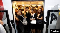 Para penumpang kereta api di Bangkok, Thailand, berpakaian warna hitam untuk menyatakan duka cita atas kematian Raja Bhumibol Adulyadej (17/10). (Reuters/Issei Kato)