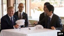 US President Donald Trump speaks with Japan's Prime Minister Shinzo Abe during a luncheon at the Kasumigaseki Country Club Gold Course in Tokyo, Nov. 5, 2017. The president and prime minister signed white hats reading “Donald and Shinzo Make Alliance Even