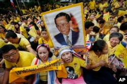 FILE - Supporters of Thailand's King Bhumibol Adulyadej, carrying portraits and banners, are seen celebarting his 87th birthday, in Bangkok, Thailand, Dec. 5, 2014.