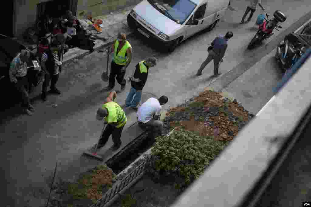 Outside the hotel, workers dig up the street while a family, unable to get in as the hotel is full, waits. (J. Owens/VOA)