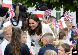 Children welcome Britain's Kate, the Duchess of Cambridge, during her visit with Prince William in front of the presidential palace, in Warsaw, Poland.
