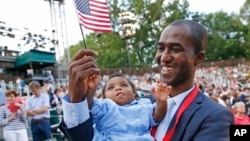미국에 정착한 아프리카 기니 출신 난민이 지난 6월 20일 '세계 난민의 날'을 맞아 뉴욕 센트럴파크에서 진행된 시민권 선서식에 딸과 함께 참석해 성조기를 흔들고 있다.