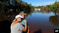 Dianna Wood, embraces her husband Lynn, as they look out over their flooded property as the Little River continues to rise in the aftermath of Hurricane Florence in Linden, North Carolina, Sept. 18, 2018. 