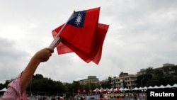 An audience member waves Taiwanese flags during the National Day celebrations in Taipei, Taiwan, Oct. 10, 2018.