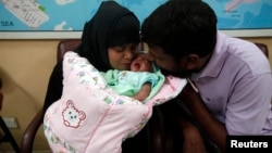 A childless couple kisses their newly adopted daughter, Fatima, whom Pakistani television talk show host Aamir Liaquat Hussain gave them on his show, as they sit at the Chhipa Welfare Association office in Karachi, Aug. 1, 2013.