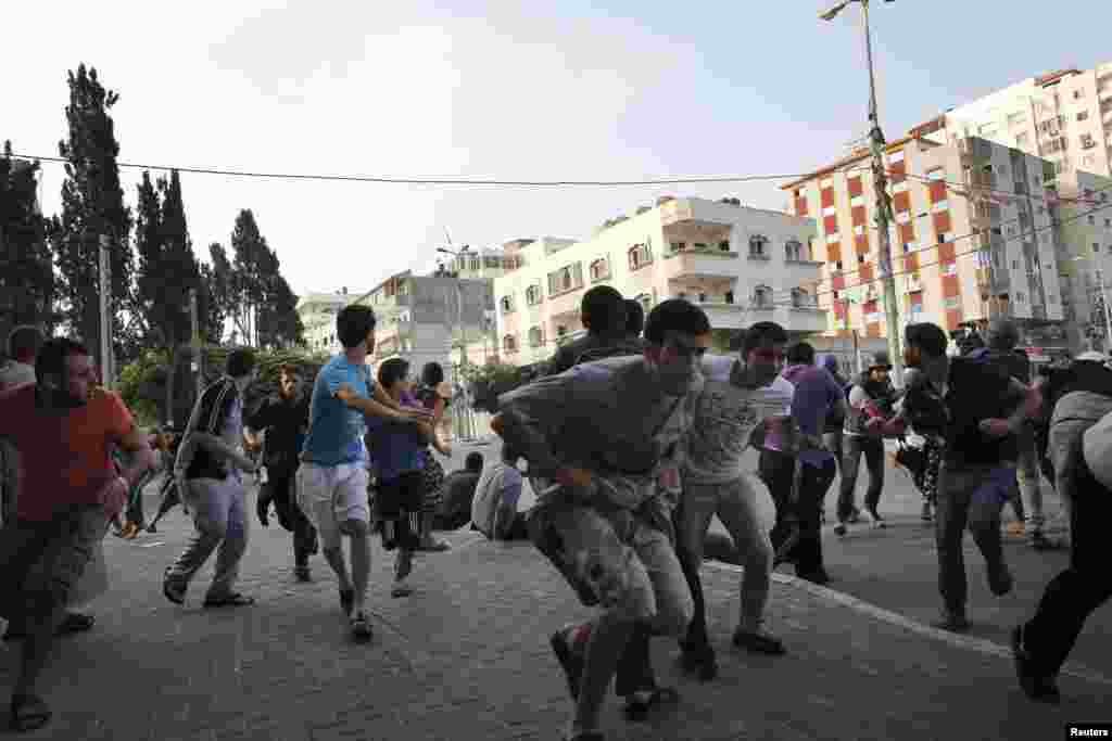 Palestinians take cover as warning Israeli air strikes are fired at a nearby building in Gaza City.