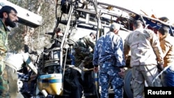 Members of Syrian security services and soldiers inspect the wreckage of a bus on which an explosion occurred, in central Damascus, Feb. 1, 2015. 