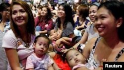 FILE - Filipino mothers hold their babies during a one-minute simultaneous breastfeeding event, as a way to promote breastfeeding, in Manila, Philippines, Aug. 5, 2017. 
