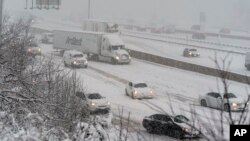 Cars and trucks slip going up a small hill on I-495, the Capital Beltway, as snow falls, Jan. 3, 2022, in Fort Washington, Maryland.