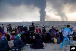 Smoke rises as people flee their homes during clashes between Iraqi security forces and members of the Islamic State group fleeing Mosul, Iraq, Oct. 18, 2016.