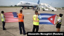 FILE - Ground crew hold U.S. and Cuban flags near a recently landed JetBlue aeroplane, the first commercial scheduled flight between the United States and Cuba in more than 50 years, in Santa Clara, Cuba, Aug. 31, 2016.