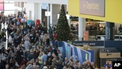 La gente espera cerca de la puerta de salidas en el aeropuerto de Gatwick, cerca de Londres, ya que el aeropuerto permanece cerrado con los vuelos entrantes retrasados o desviados a otros aeropuertos.