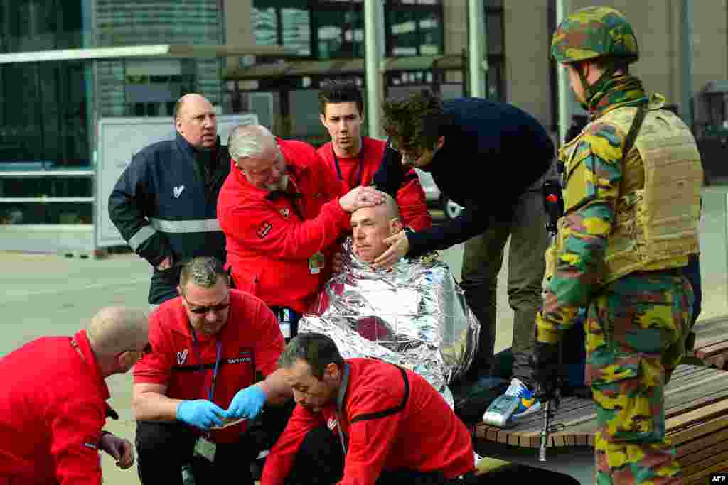 Seorang korban menerima pertolongan pertama dari petugas darurat dekat stasiun metro Maalbeek di Brussels, menyusul sebuah ledakan dekat markas besar Uni Eropa yang menyebabkan korban tewas dan terluka (22/3). (AFP/Emmanuel Dunand)