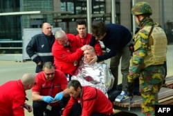 A victim receives first aid by rescuers, on March 22, 2016 near Maalbeek metro station in Brussels, after a blast at this station near the EU institutions caused deaths and injuries.