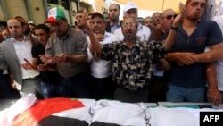 Palestinian men pray over the body of Saed Dawabsha, the father of a Palestinian toddler killed last week when their home was firebombed by suspected Jewish extremists, during his funeral in the West Bank village of Duma, Aug. 8, 2015. 