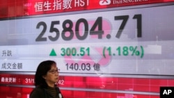 A woman passes an electronic board showing the Hong Kong share index outside a bank in Hong Kong, Dec. 31, 2018.