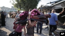 A Palestinian girl carries belongings as she and her family leave the Abu Hussein U.N. school in the Jebaliya refugee camp, northern Gaza Strip, hit by an Israeli strike earlier, July 30, 2014.