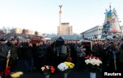 Pallbearers carry the coffins of those killed in Thursday's clashes during a service in Independence Square in Kyiv, Feb. 21, 2014.