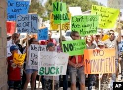 FILE - Protesters in Utah hold signs denouncing a move to designate land as a national monument, July 14, 2016.