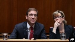 Portuguese Prime Minister Pedro Passos Coelho and Finance Minister Maria Luis Albuquerque, right, look at a wall clock during the debate of the government's four-year policy program at the Parliament in Lisbon, Nov. 10, 2015.