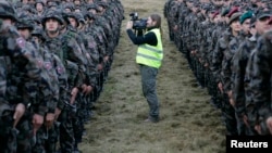 FILE - A cameraman films soldiers after a military exercise in Pocek, Slovenia.