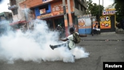 A demonstrator kicks a tear gas canister during clashes with Haitian police in Port-au-Prince, Feb. 15, 2019, on the ninth day of protests against Haitian President Jovenel Moise.