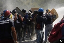 Anti-government protesters clash with riot police, encountering water cannon spray, during a march toward the Ombudsman's Office in Caracas, Venezuela, May 29, 2017.