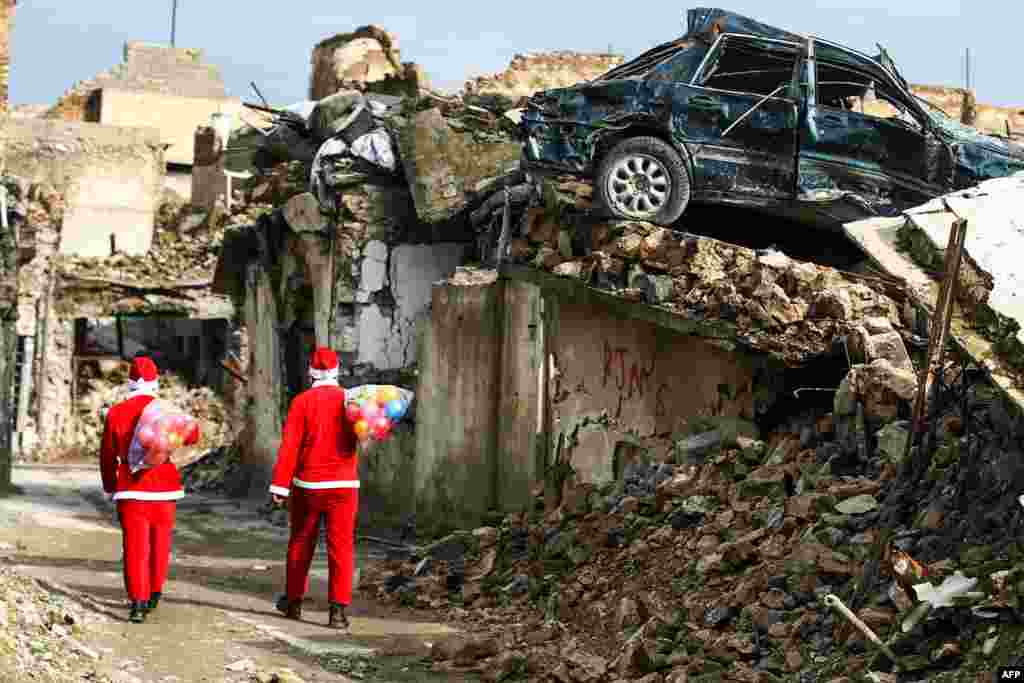 Iraqi youths dressed in Father Christmas suits walk through the streets of the old city of Mosul to distribute gifts to the children.
