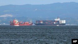 FILE - In this June 17, 2017, photo, the damaged Philippine-registered container ship ACX Crystal, right, cruises past another container ship off Yokosuka, south of Tokyo, after colliding with the USS Fitzgerald off Japan earlier in the day, tha