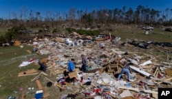 Cindy Sanford, second from right, sifts through the debris with help from her family while retrieving personal items after a tornado destroyed Sanford's home in Beauregard, Ala., March 5, 2019.