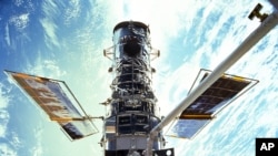 En esta imagen provista por la NASA, los astronautas Steven Smith y John Grunsfeld realizan trabajos de mantenimiento del Telescopio Espacial Hubble en diciembre de 1999. 