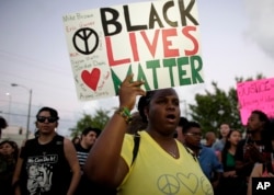 FILE - Desiree Griffiths holds up a sign saying "Black Lives Matter," with the names of Michael Brown and Eric Garner, two black men killed by police, during a protest in Miami, Florida, Dec. 5, 2014.