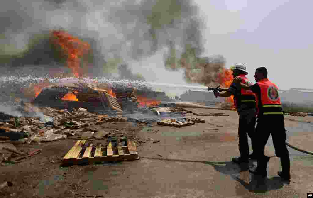 Palestinian firefighters try to extinguish a cargo terminal at Karni Crossing between Israel and Gaza after it was shelled by Israeli tanks, according to terminal's employees, July 12, 2014. 