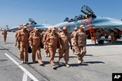 In this file photo taken June 18, 2016, Russian Defense Minister Sergei Shoigu, center, visits the Hemeimeem air base in Syria