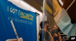 Los Angeles Unified Superintendent Austin Beutner takes pictures with high school students, as a Licensed Vocational Nurse prepares Pfizer vaccines. (AP Photo/Damian Dovarganes)