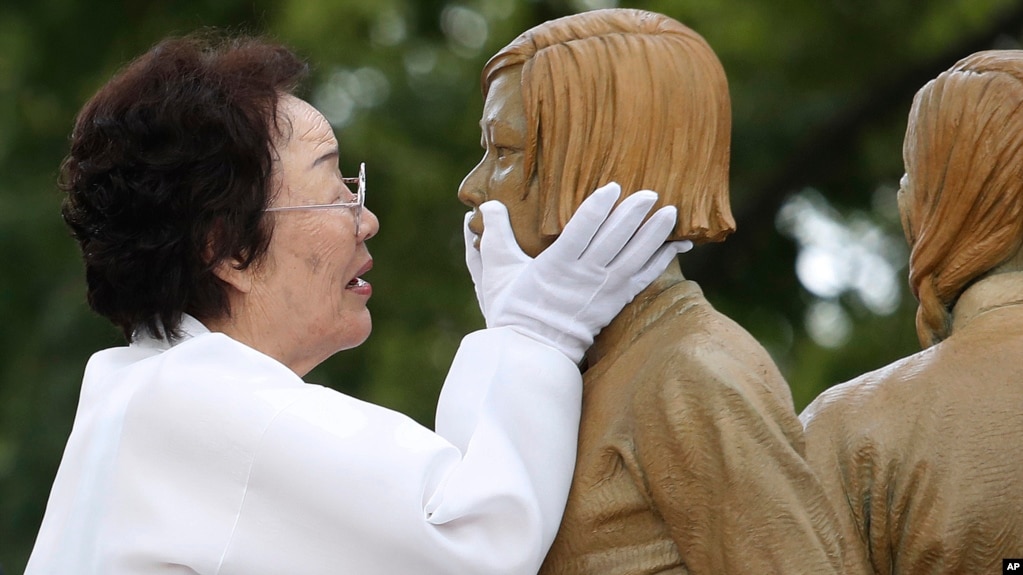 In this Aug. 14, 2019, file photo, Lee Yong-soo, who was forced to serve for the Japanese troops as a sex slave during World War II, touches the face of a statue of a girl symbolizing "comfort women" during its unveiling ceremony in Seoul, South Korea. (AP Photo)