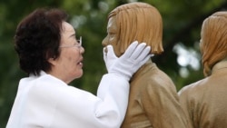 在韩国首尔，二战期间被迫成为日军性奴的李永洙在一尊象征战时“慰安妇”的少女雕像揭幕仪式上触摸雕像的脸。（2019年8月14日）