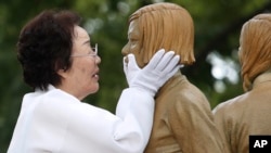 In this Aug. 14, 2019, file photo, Lee Yong-soo, who was forced to serve for the Japanese troops as a sex slave during World War II, touches the face of a statue of a girl symbolizing "comfort women" during its unveiling ceremony in Seoul, South Korea. (AP Photo)