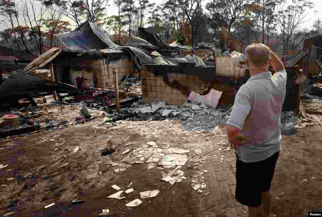 Local resident Colin Smith looks at the remains of his family's house after it was destroyed by a bushfire in the Blue Mountains suburb of Winmalee, located around 70 km west of Sydney, Australia.